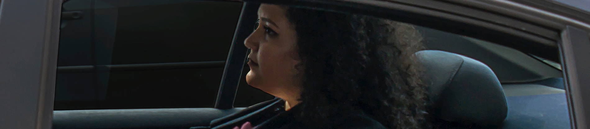 A women sat in the back of a car looking forward A women sat in the back of a car looking forward