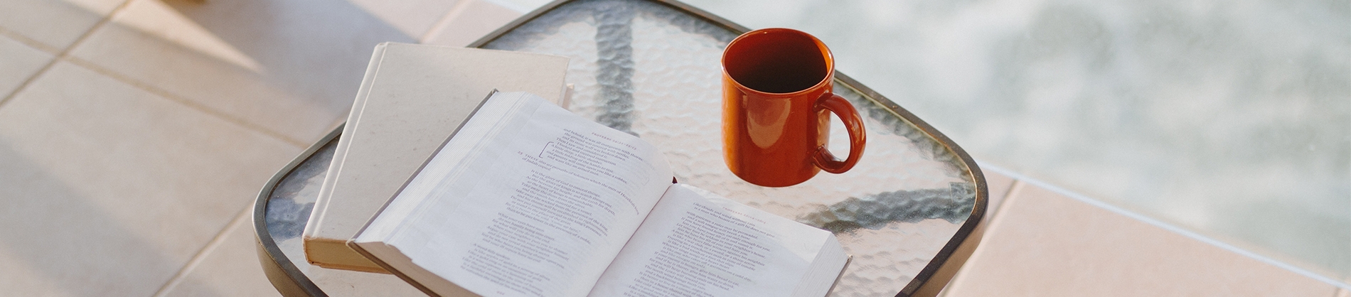 Open bible, notebook and cup of coffee on a glass table by the pool Open bible, notebook and cup of coffee on a glass table by the pool