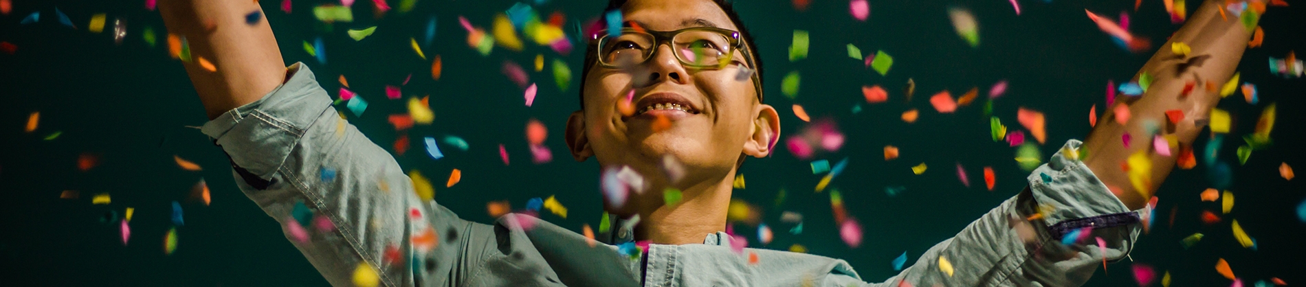 A guy smiling with his arms in the air and confetti falling around him A guy smiling with his arms in the air and confetti falling around him