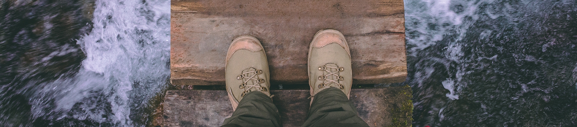A man stood on a wooden bridge over a river A man stood on a wooden bridge over a river