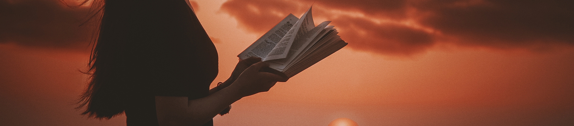 Women stood in front of a sunset with her bible open