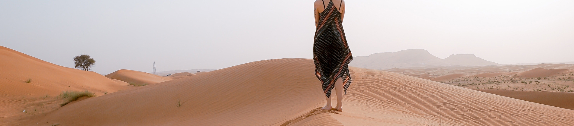 A women walking along sand dunes A women walking along sand dunes