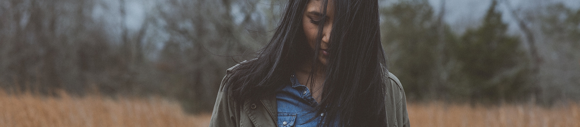 A women stood in a field looking down at the ground A women stood in a field looking down at the ground