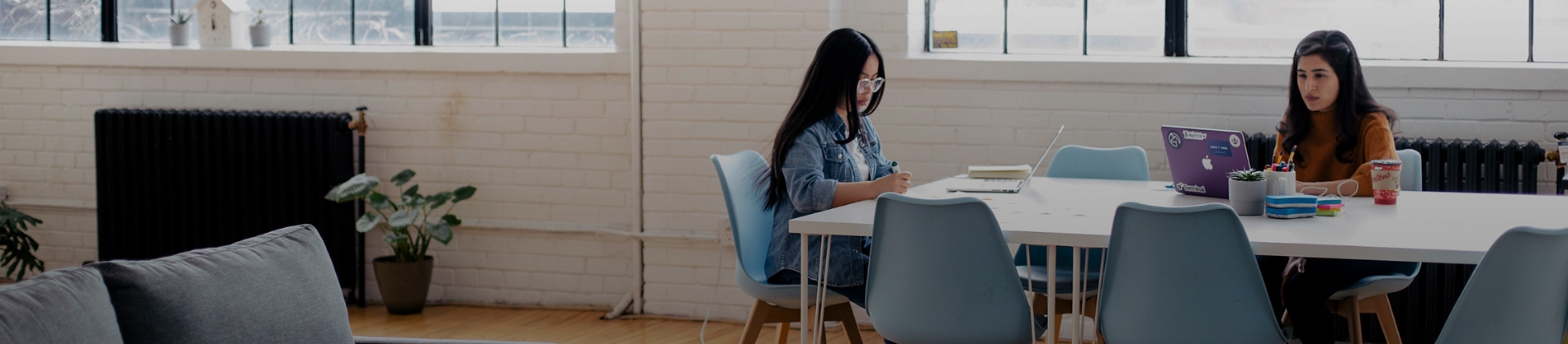 Two women sat at a table working on laptops Two women sat at a table working on laptops