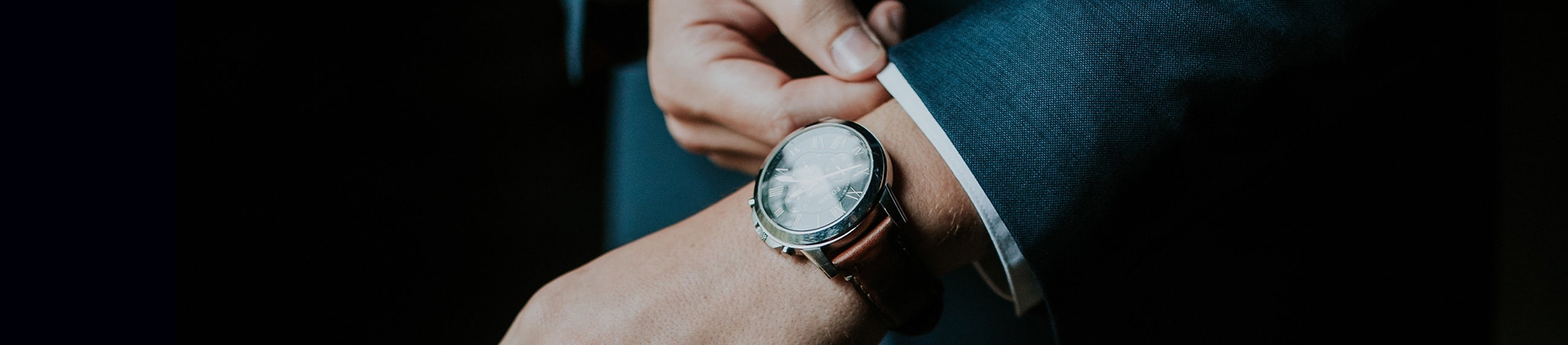 A man wearing a suit showing off a watch A man wearing a suit showing off a watch