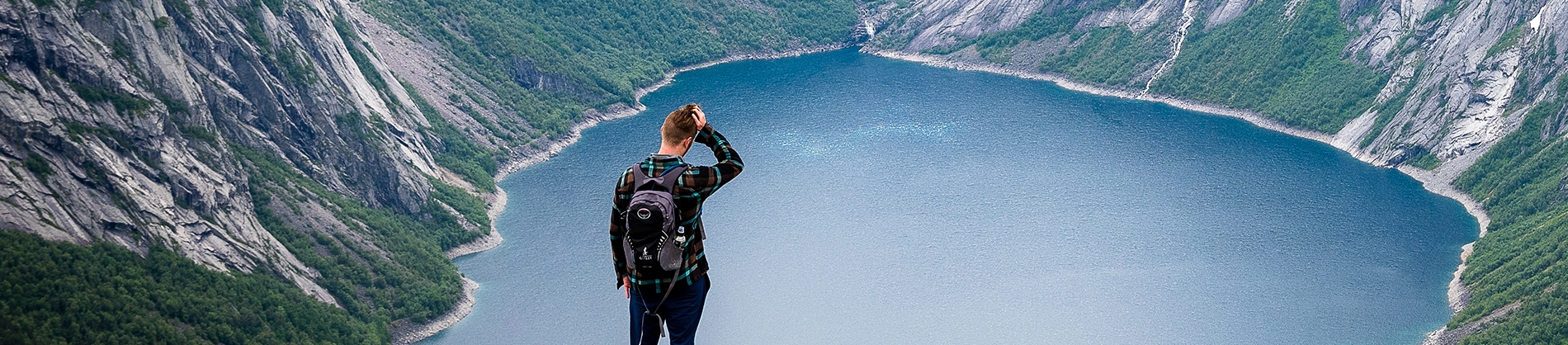 A man stood looking down to a lake in a valley A man stood looking down to a lake in a valley