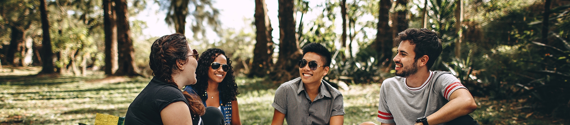 A group of friends sat laughing and smiling in a park