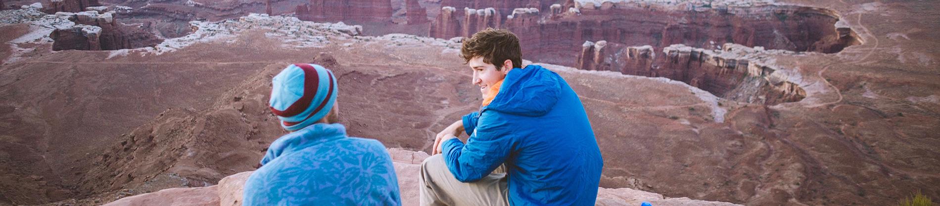 Two men sat on top of a mountain talking