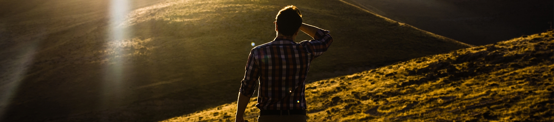 A man looking towards a sunset over a hill A man looking towards a sunset over a hill