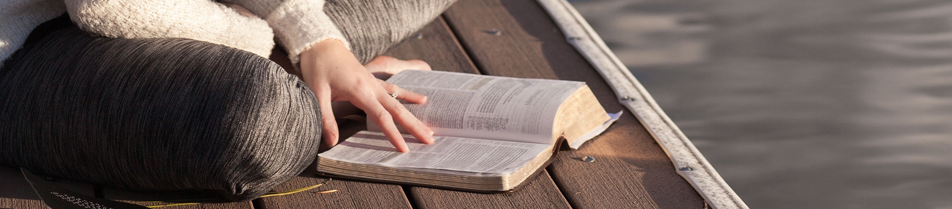 A women sat on a dock reading her bible A women sat on a dock reading her bible