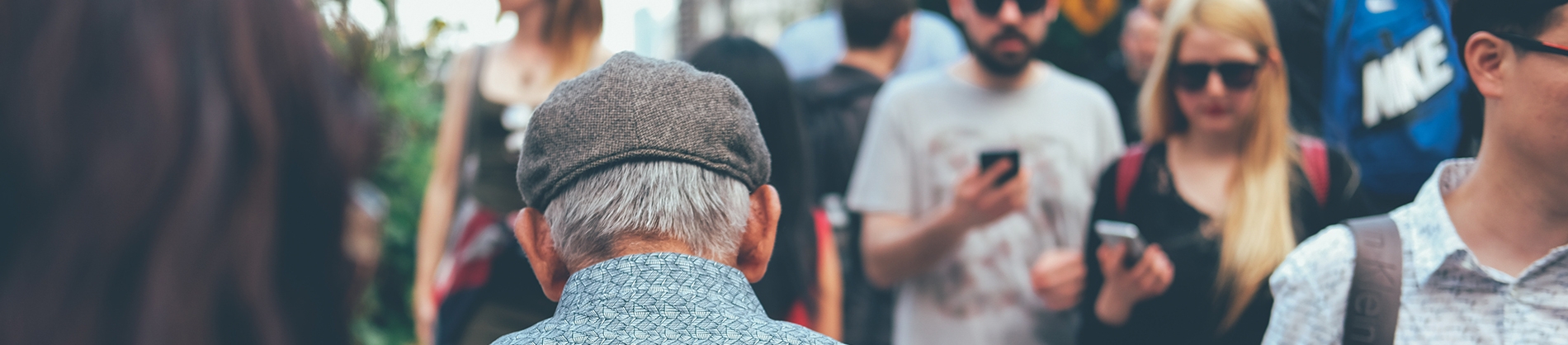 A elderly man walking down a street full of people