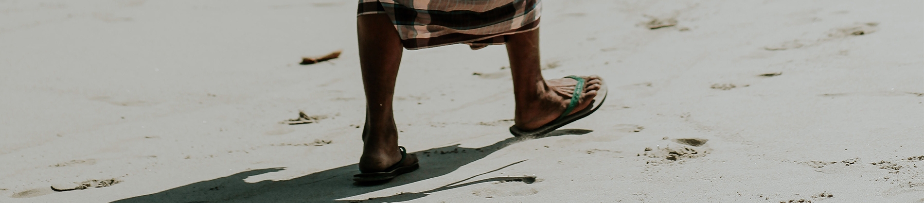 A women in sandals walking across a beach A women in sandals walking across a beach