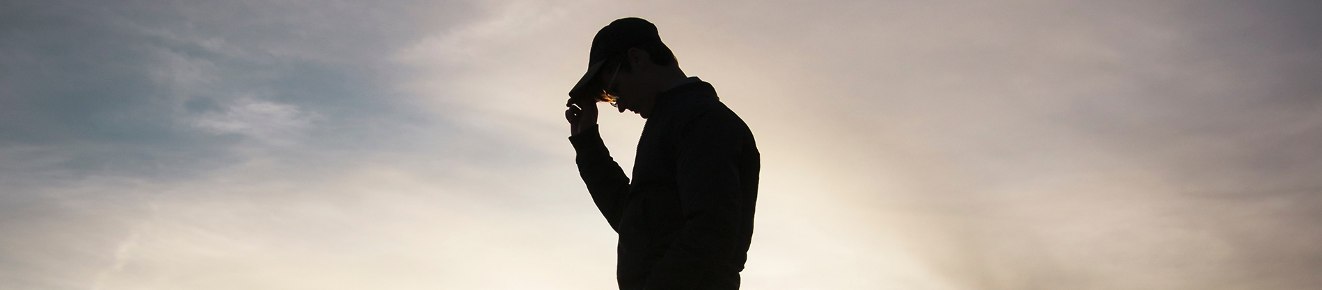 A silhouette of a man holding his cap A silhouette of a man holding his cap