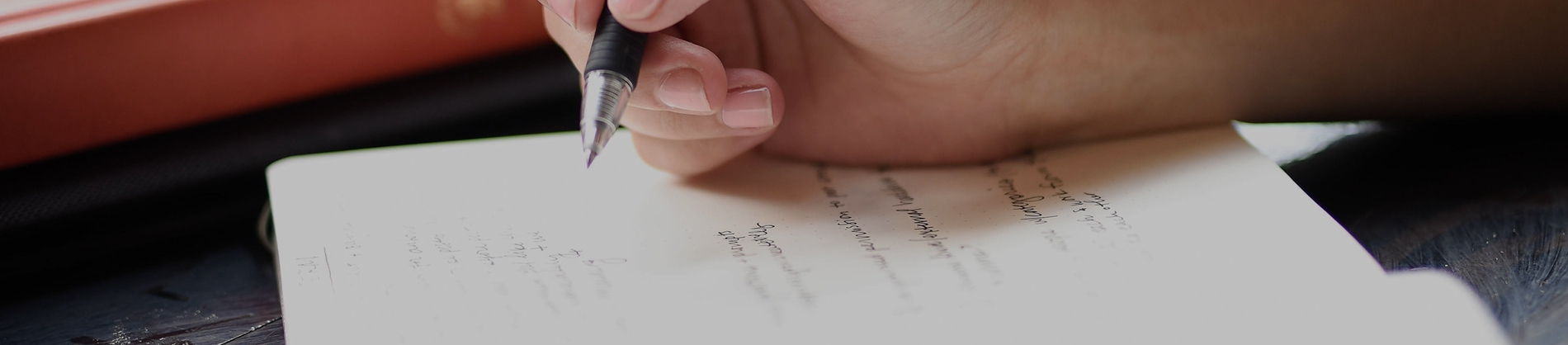 A women writing in a notebook with a black pen A women writing in a notebook with a black pen