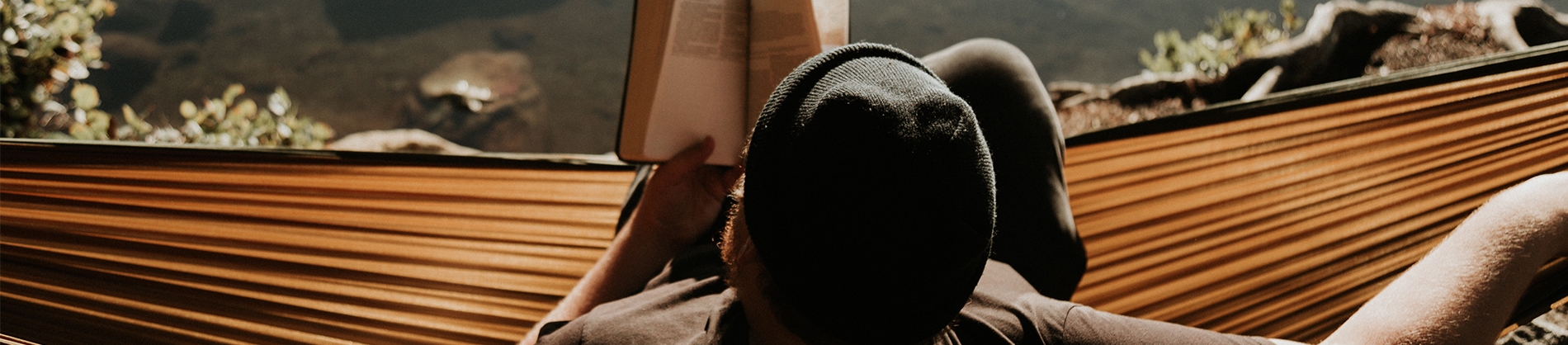 A man sat on a hammock reading his bible A man sat on a hammock reading his bible