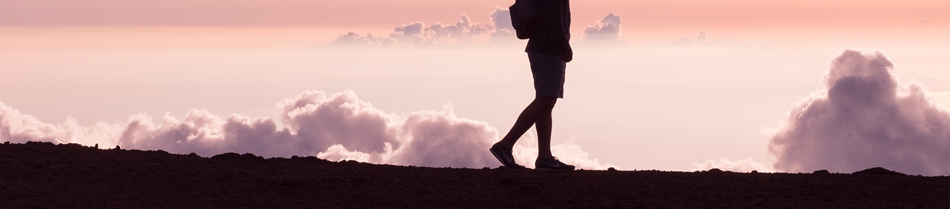 A man walking along path with sunset behind him A man walking along path with sunset behind him