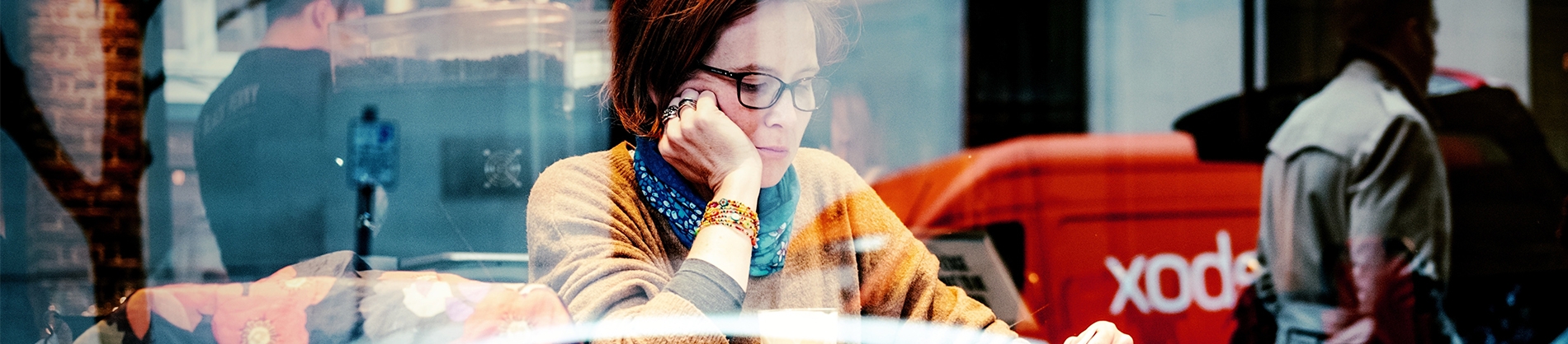 A women sat in a cafe window reading A women sat in a cafe window reading