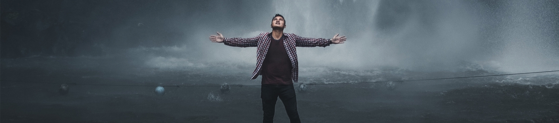 A man in a checked shirt with his arms wide in front of a cloudy landscape A man in a checked shirt with his arms wide in front of a cloudy landscape