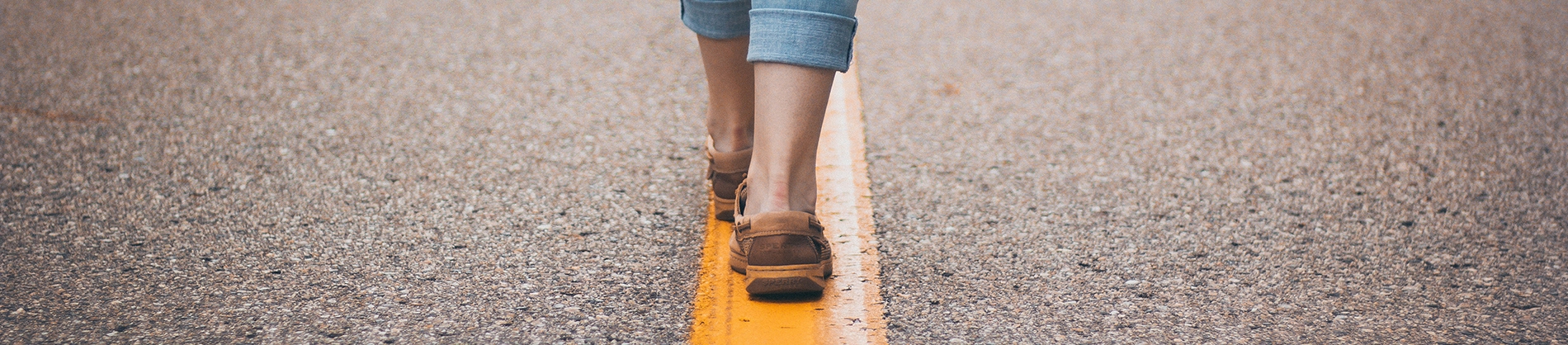 A women walking along a yellow line on a tarmac road A women walking along a yellow line on a tarmac road