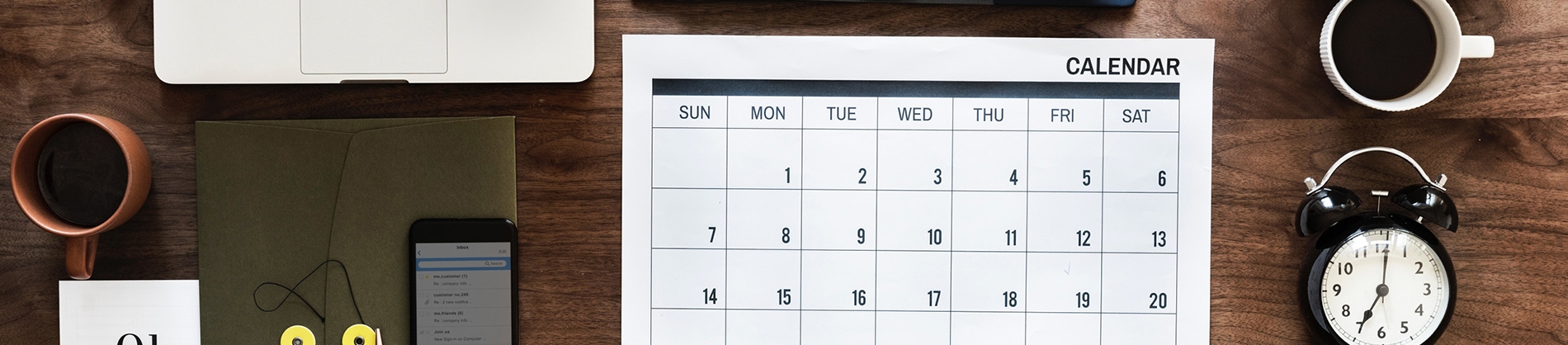 A wooden desk with a calendar, clock and phone on A wooden desk with a calendar, clock and phone on