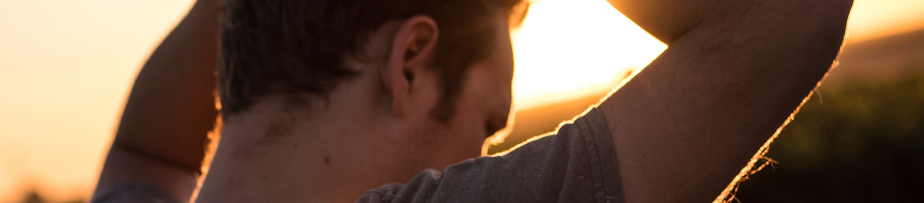 A man with his hands on his head, with the sunset in front of him A man with his hands on his head, with the sunset in front of him