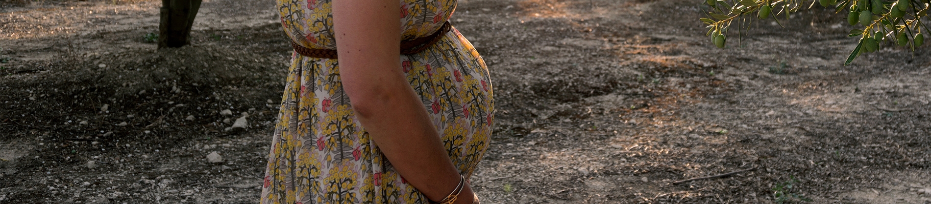 A pregnant women in a dress stood in a park A pregnant women in a dress stood in a park