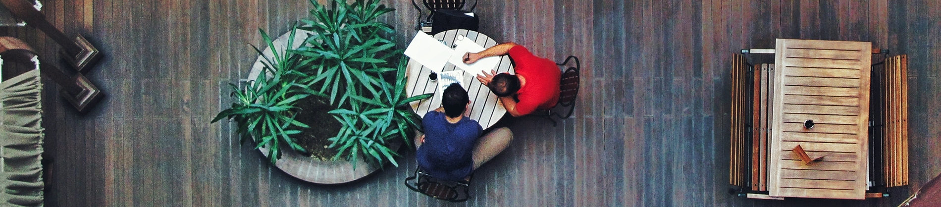Two guys sat working together on a round table Two guys sat working together on a round table