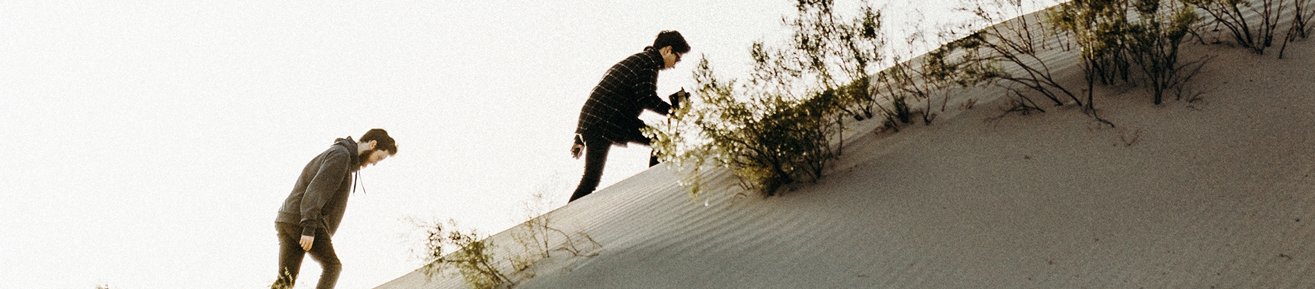 Two guys climbing up a sandy hill Two guys climbing up a sandy hill