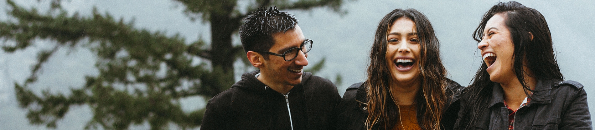 Three friends laughing together with a mountain landscape behind Three friends laughing together with a mountain landscape behind