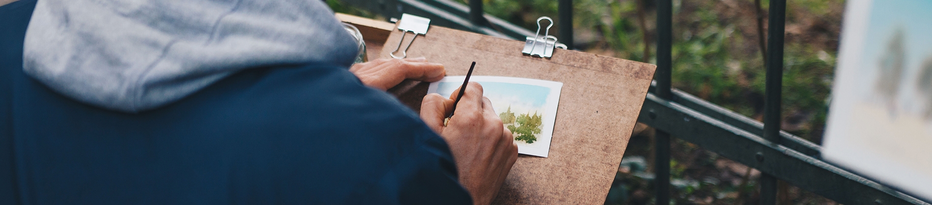 A man painting onto a small piece of paper A man painting onto a small piece of paper