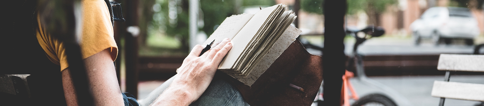 A women sat on a bench writing in a notebook A women sat on a bench writing in a notebook