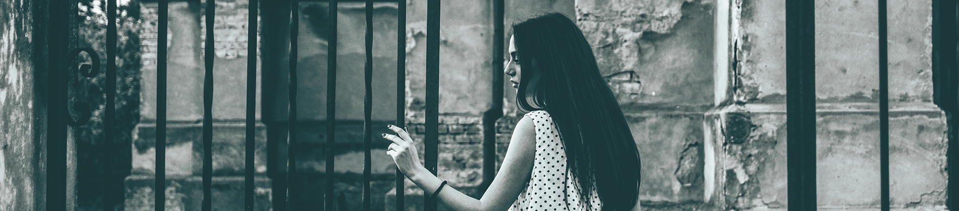 A black and white photo of a women pushing open iron gates into a church courtyard A black and white photo of a women pushing open iron gates into a church courtyard