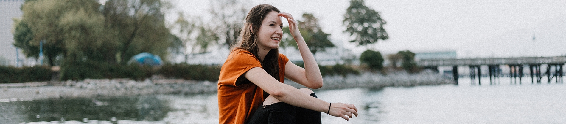 A women sat with the sea and pier behind her A women sat with the sea and pier behind her