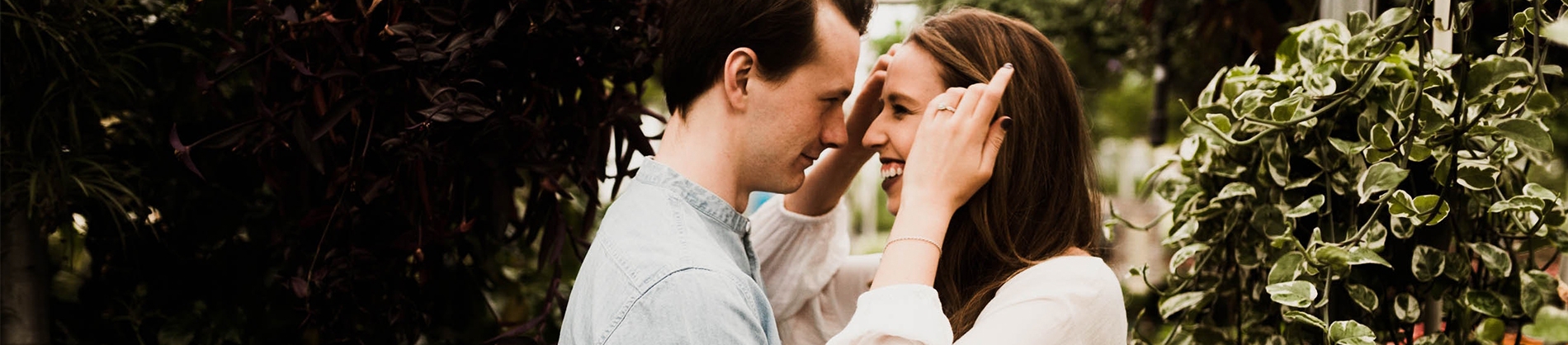 A couple smiling together surrounded by trees A couple smiling together surrounded by trees