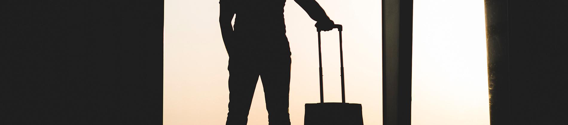 A man stood in-front of a window with a suitcase