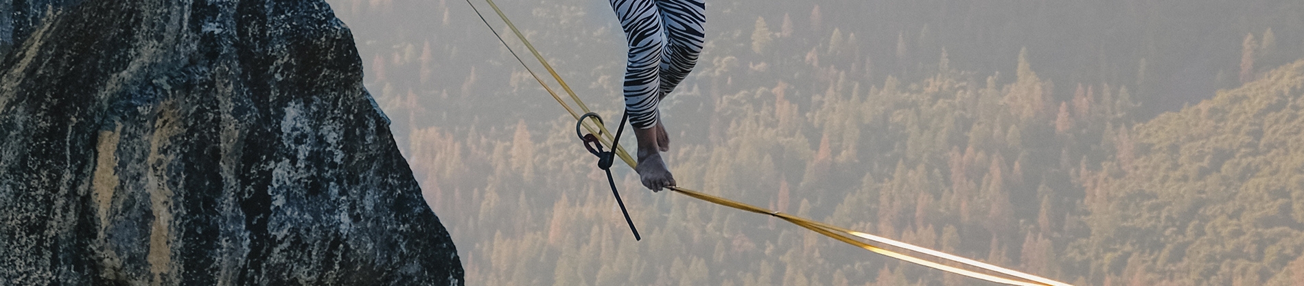 A person walking on a tightrope over a valley A person walking on a tightrope over a valley