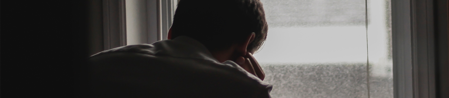 A man sat near a window leaning on his hand A man sat near a window leaning on his hand