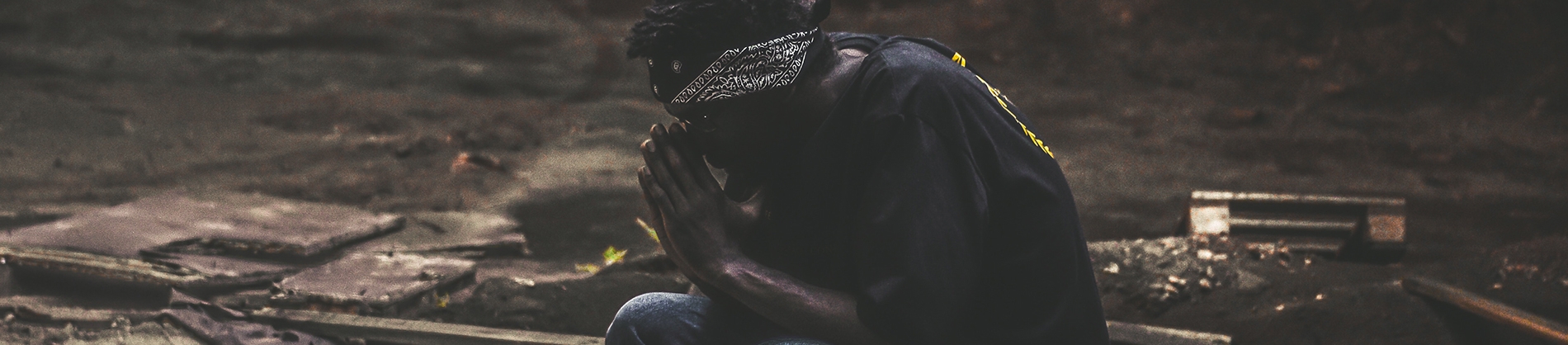 A guy crouching on the floor praying