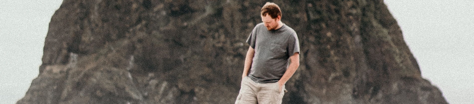 A man walking along a beach with his hands in his pockets A man walking along a beach with his hands in his pockets