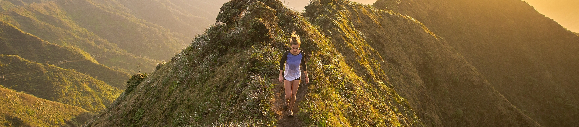 A women running down a hill with the sun rising behind her