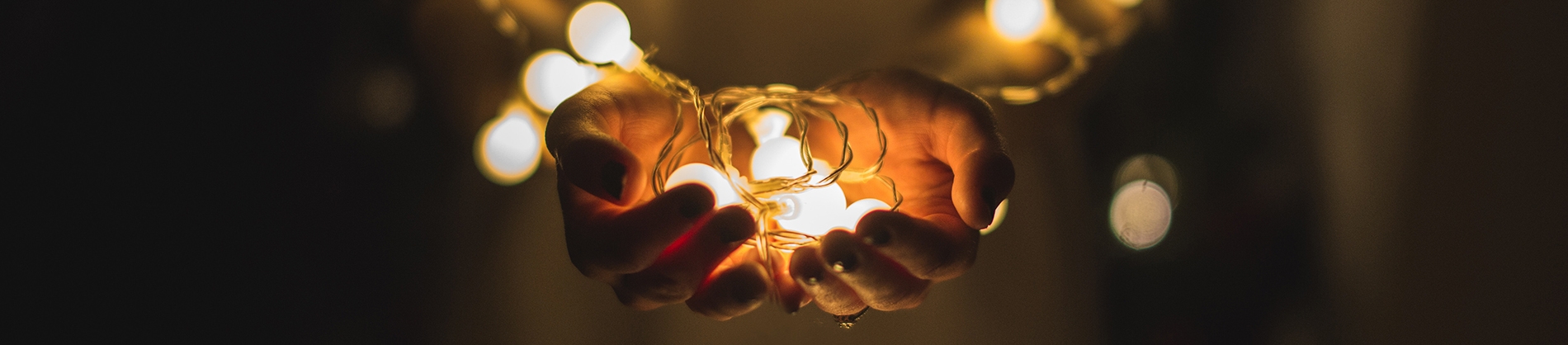 A women holding small lit lightbulbs A women holding small lit lightbulbs