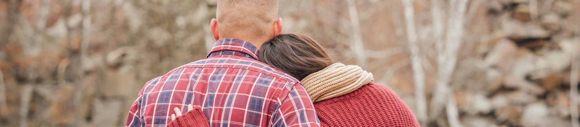 A women resting her head on a mans shoulder with arms around each other