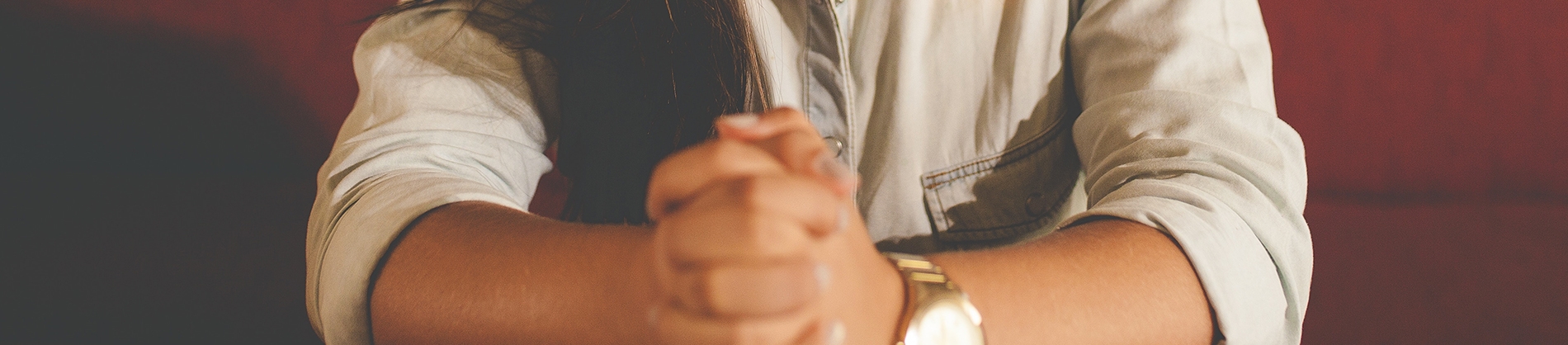 A women sat with her hands together praying A women sat with her hands together praying