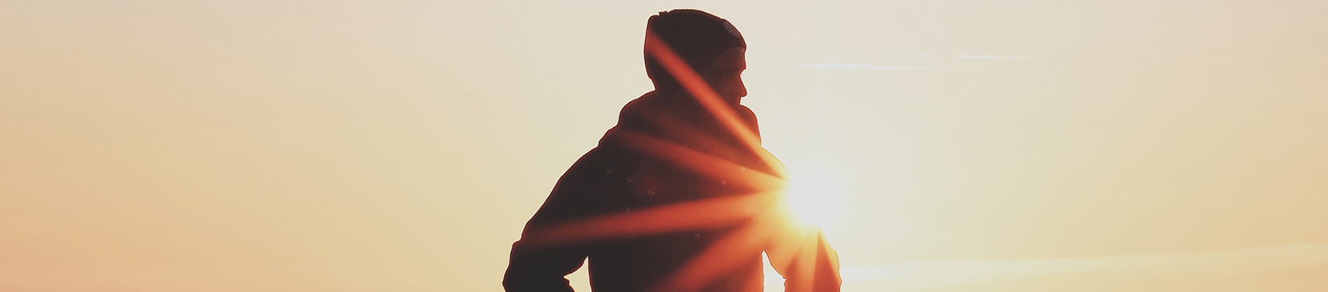 A silhouette of a man standing in front of the sunset A silhouette of a man standing in front of the sunset
