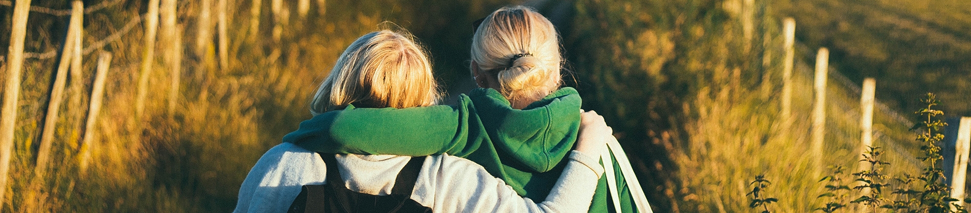 Two women with their arms around each other walking down a path Two women with their arms around each other walking down a path