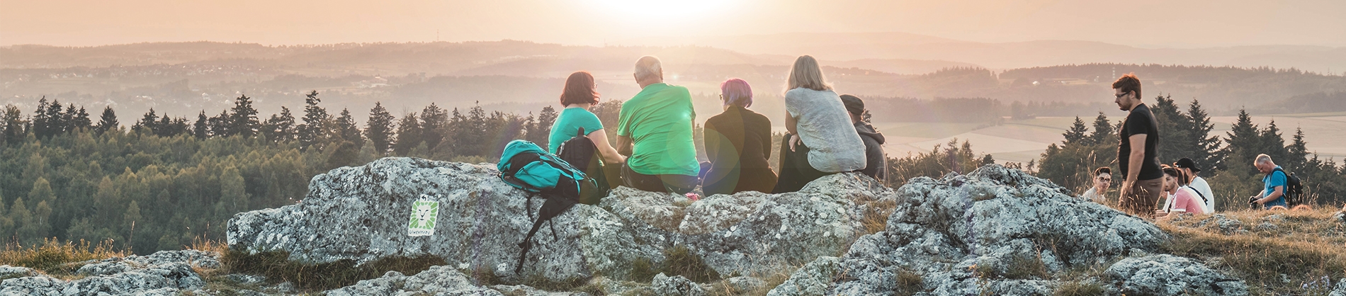 A family sat on a rock looking over a mountain landscape A family sat on a rock looking over a mountain landscape