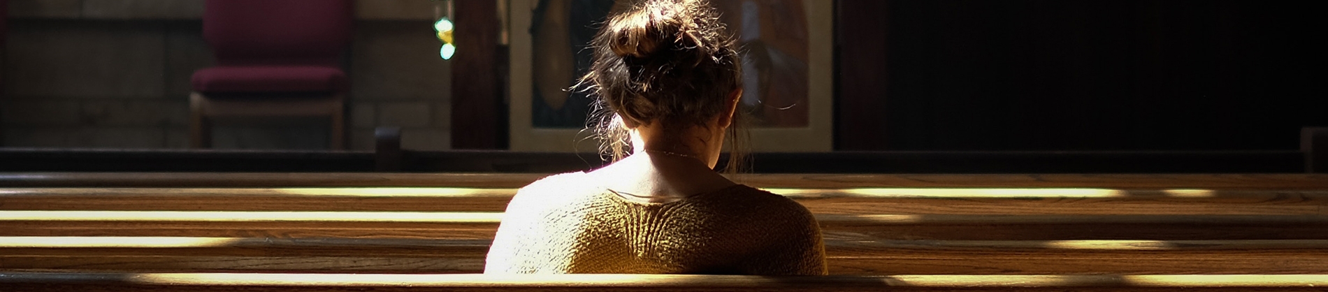 A women sat along in a church pew A women sat along in a church pew