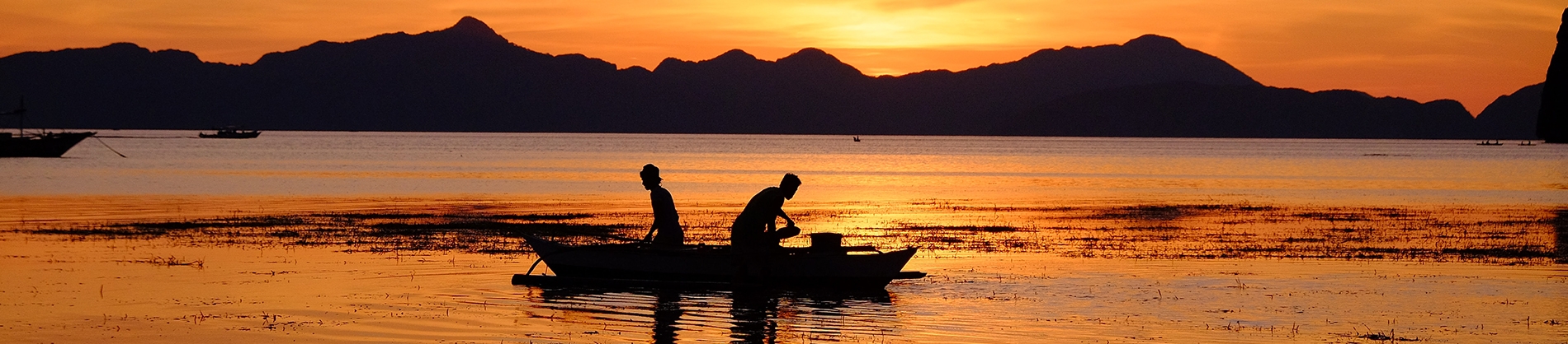 Two fishermen out on a boat at sunrise Two fishermen out on a boat at sunrise