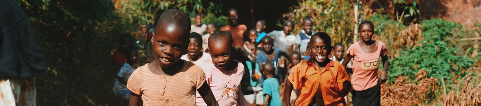 A group of happy African children running down a road