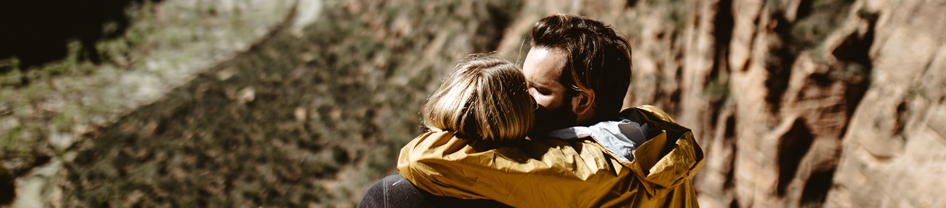 A man and women looking over a cliff hugging